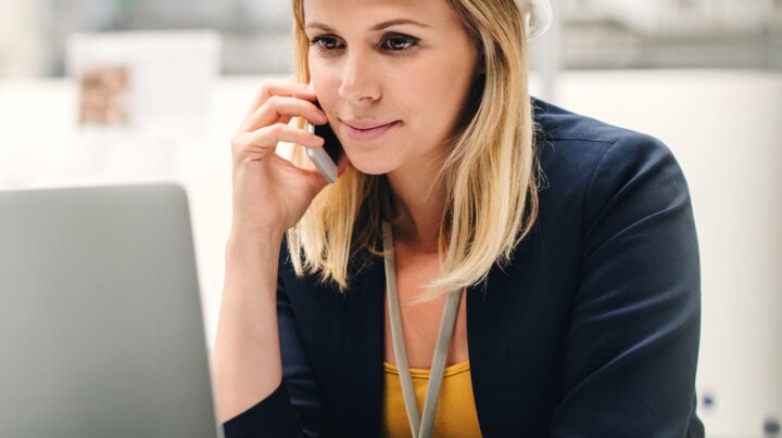 A female employee on the phone wearing a health & safety helmet