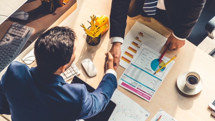 Group business people handshake at meeting table in office together with confident shot from top view.