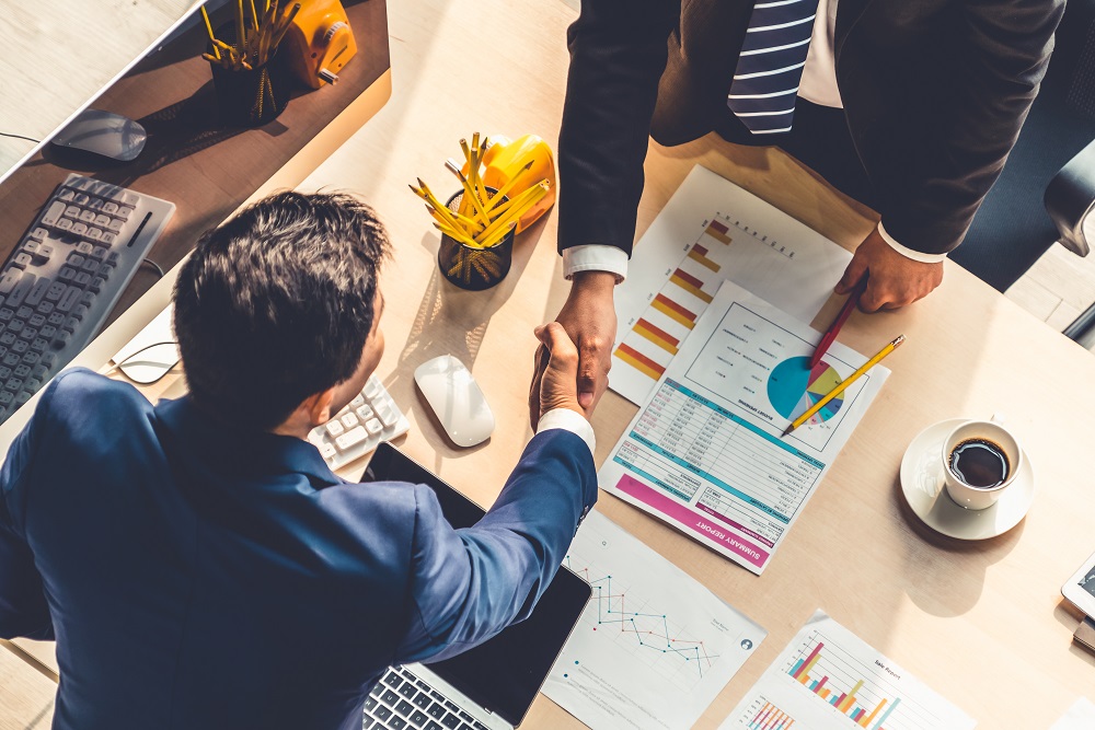 Group business people handshake at meeting table in office together with confident shot from top view.