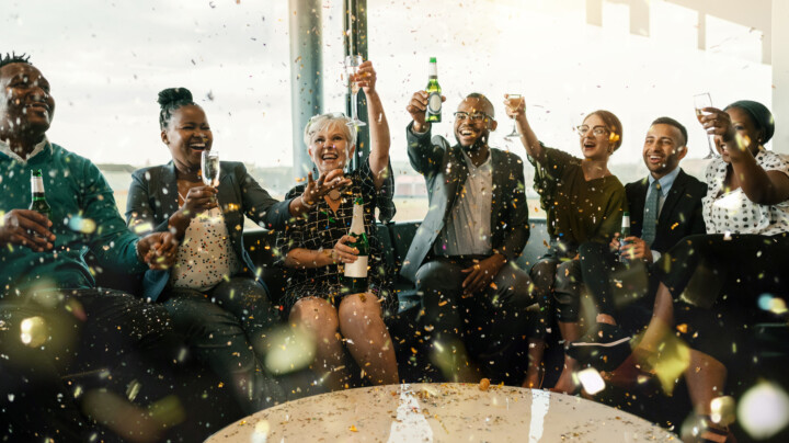 Group of employees smiling and celebrating with champagne and alcohol