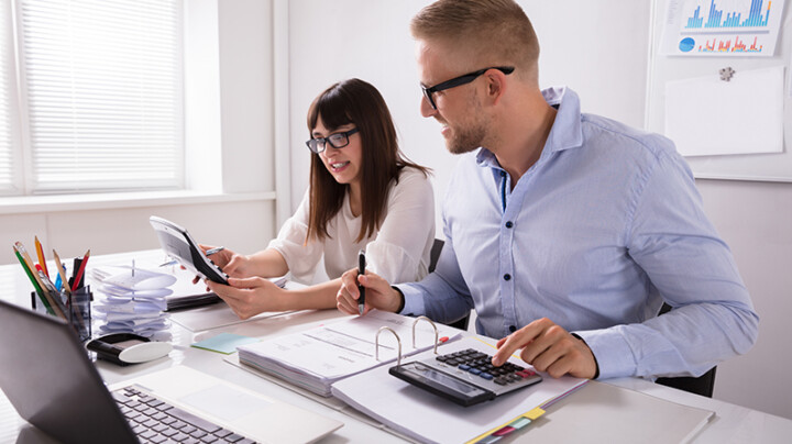 Two employees collaborating and calculating on their devices