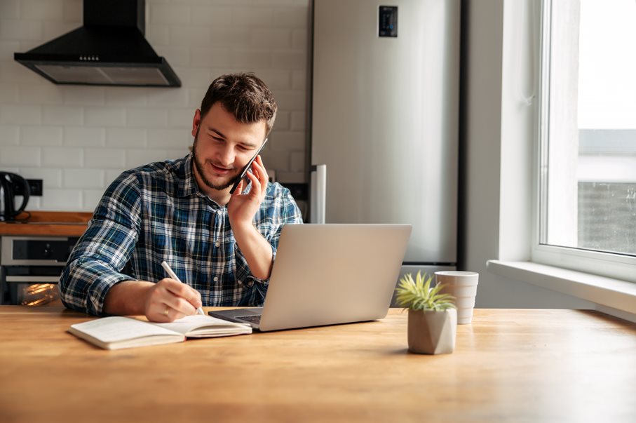 A happy male employee working from home on the phone