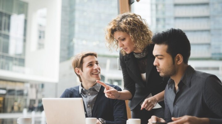 Image of a female supervisor collaborating with two men in an informal coffee setting about health and safety business partner subscriptions