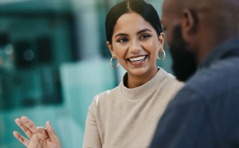 A happy female employee showing her male colleague something on a digital tablet
