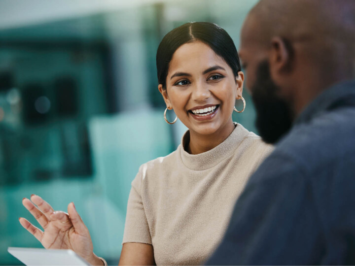 A happy female employee showing her male colleague something on a digital tablet