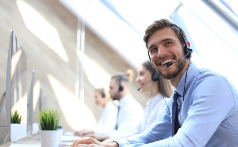 A happy call centre employee sitting with his team.