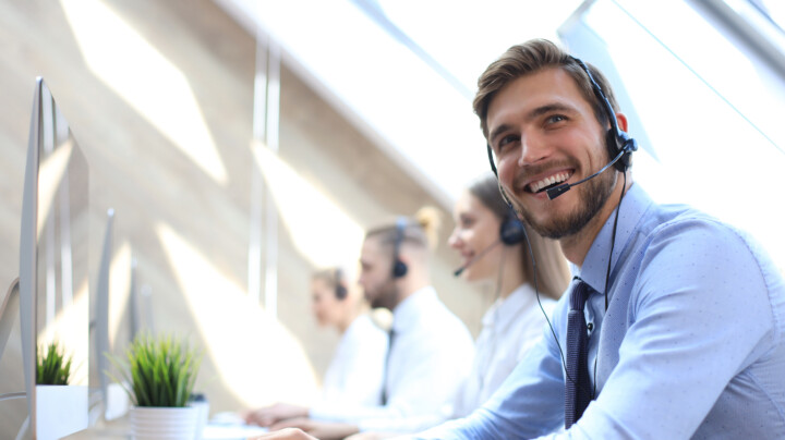 A happy call centre employee sitting with his team.