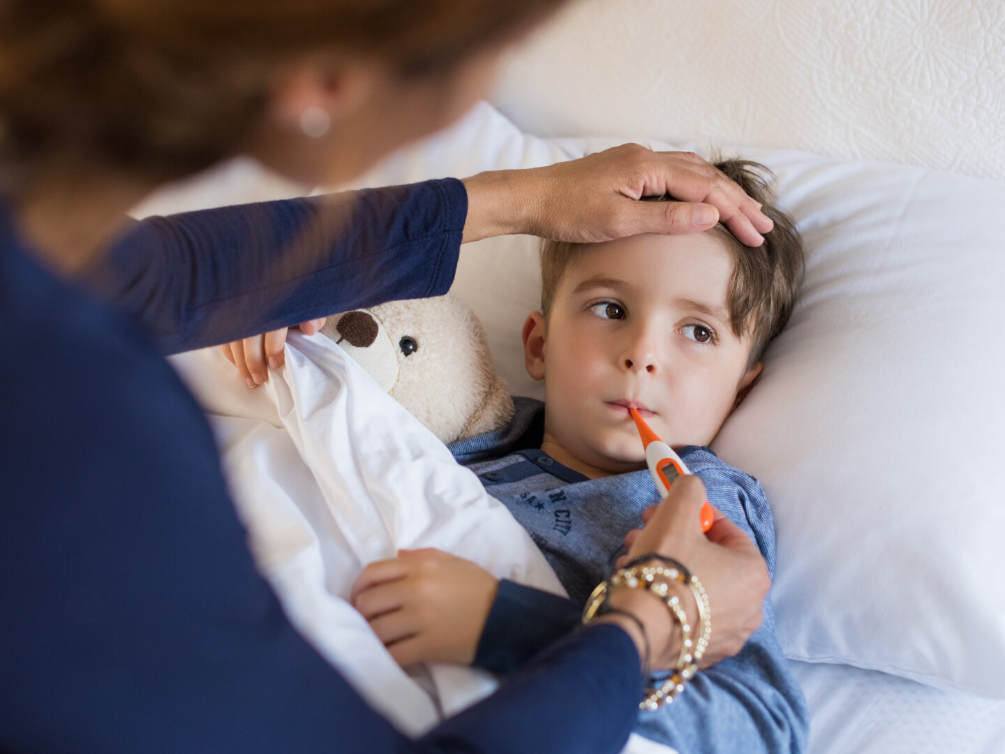 Mother measuring young child's fever