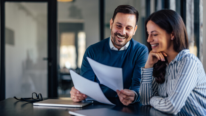 Happy male employee showing some documents to his female colleague