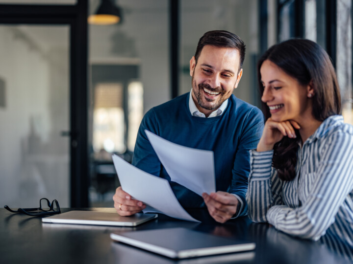 Happy male employee showing some documents to his female colleague