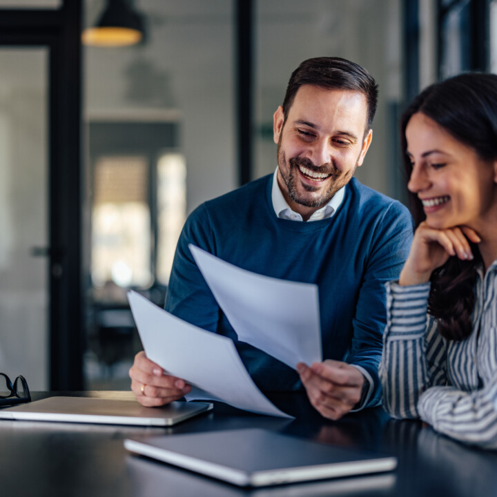 Happy male employee showing some documents to his female colleague