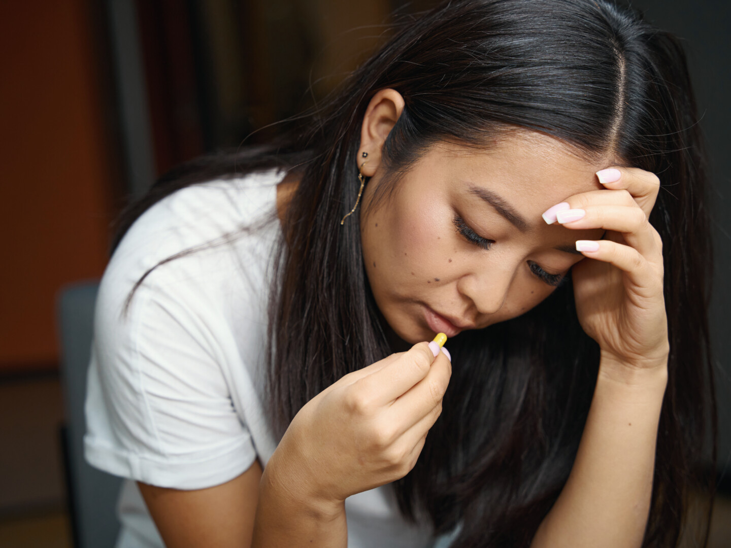 Tired woman about to swallow a pill