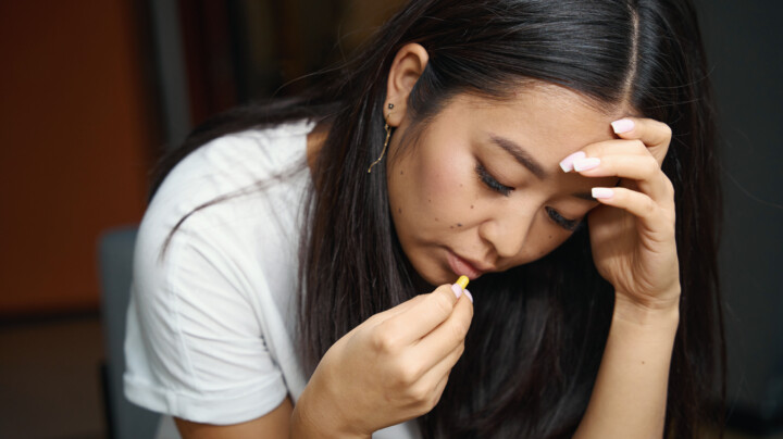 Tired woman about to swallow a pill