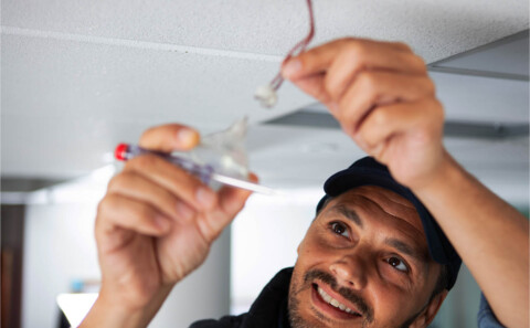 Happy electrician fixing a light bulb