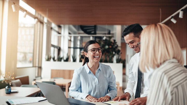 Businesspeople laughing while working at an office table