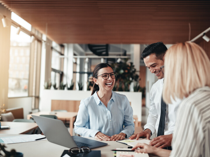 Businesspeople laughing while working at an office table